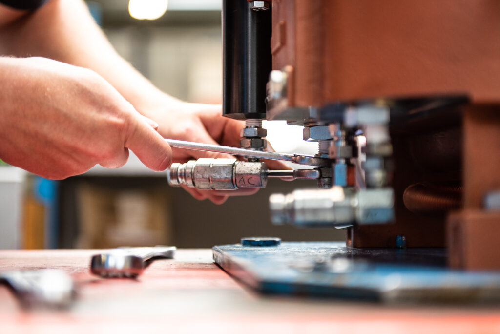 Close up industrial photography of a man's hands while working on a component in a manufacturing facility