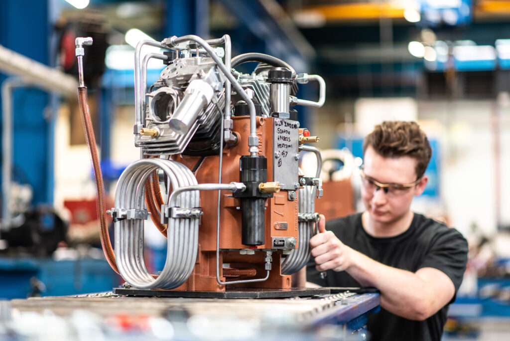 Industrial photography of a man in a factory working on an industrial compressor unit