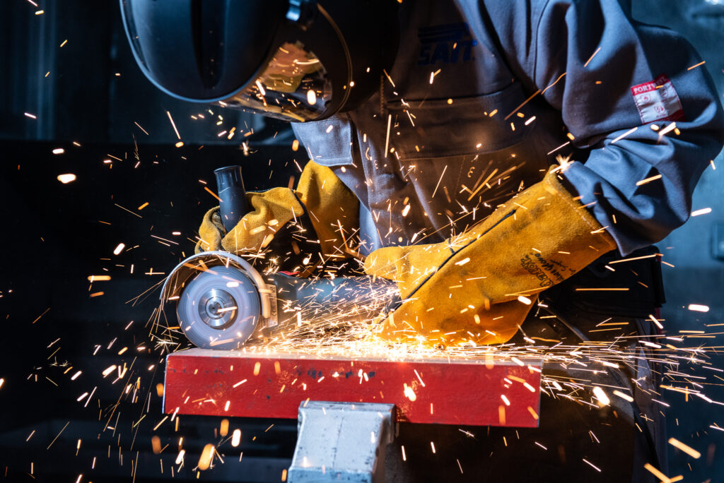 Industrial photography of a man grinding metal and sparks flying