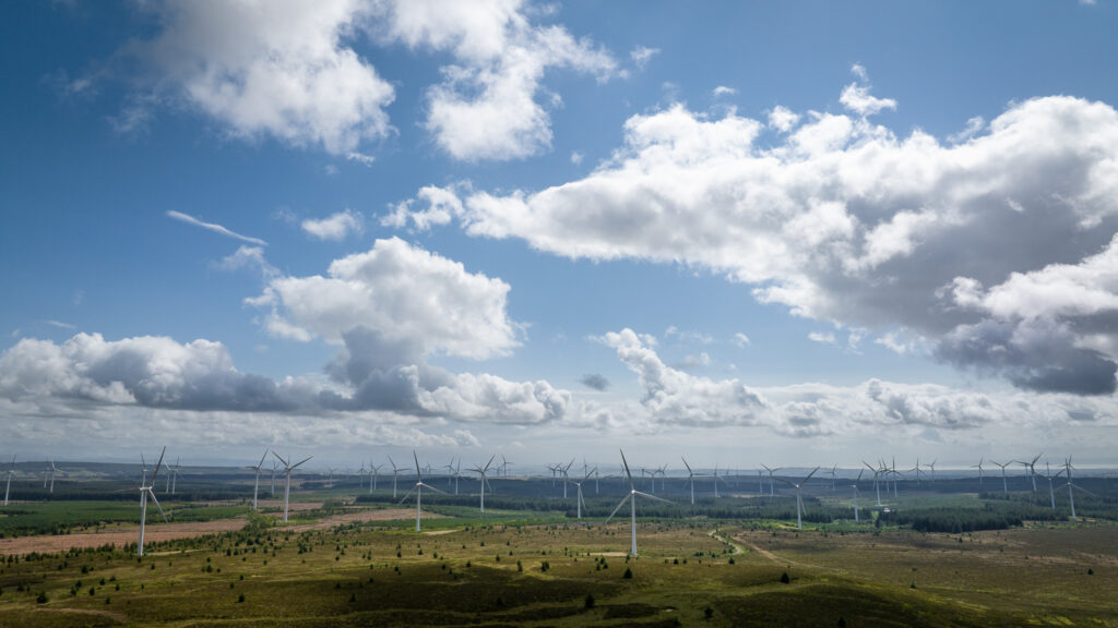 Drone photography of a wind farm on a sunny day with fluffy clouds in the sky